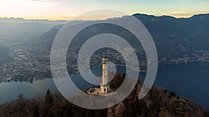 Aerial drone view of a lighthouse over Lake Como skyline with sunset light
