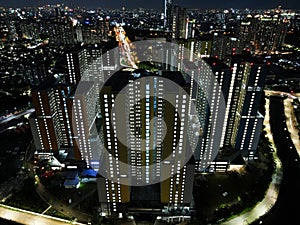 Aerial drone view of modern apartment building in Jakarta central business district at night with Jakarta cityscape. JAKARTA,