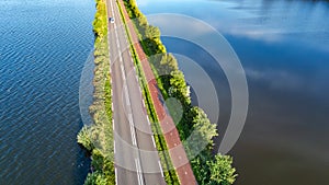 Aerial drone view of motorway road and cycling path on polder dam, cars traffic from above, Holland, Netherlands