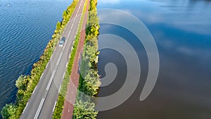 Aerial drone view of motorway road and cycling path on polder dam, cars traffic from above, Holland, Netherlands