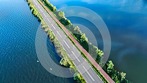 Aerial drone view of motorway road and cycling path on polder dam, cars traffic from above, North Holland, Netherlands