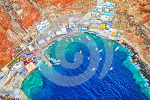 Aerial drone view of Old port Amoudi bay in Oia village with fishing boats. Santorini island in Aegean sea, Greece