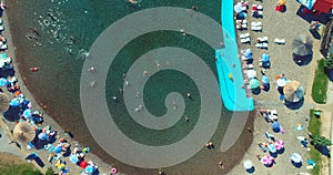 Aerial drone view of overcrowded urban lake during peak of tourist season. Crowd of people swimming in the sea at summer