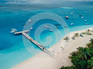 Aerial drone view of paradise Maldives tropical beach with pier and speed boats on island. Summer and travel vacation concept