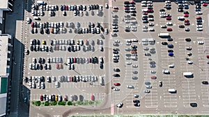 Aerial drone view of parking lot with many cars near shopping mall from above, city transportation