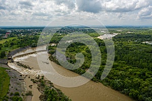 Aerial drone view. River water move down from with a water filled dam after heavy floods and rains. Wide shot