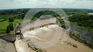 Aerial drone view. River water move down from with a water filled dam after heavy floods and rains. Wide shot V4