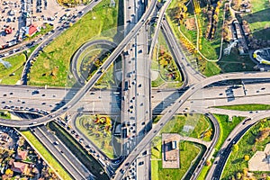 Aerial drone view of road interchange or highway intersection with busy urban traffic in modern city during sunny day. Traffic jam