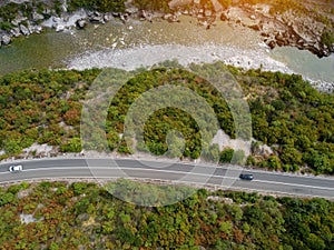 Aerial drone view of rocky canyon Moraca river with big stone boulders, asphalt road with moving cars, Montenegro