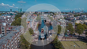 Aerial drone view of a ship passing elevating road bridge in amsterdam canal. Ship under open bridge over the canal