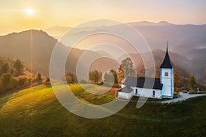 Aerial drone view of small beautiful church on a mountain in Slovenia at dawn Beautiful autumn morning landscape