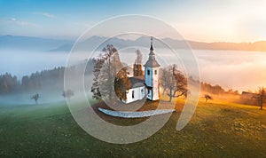Aerial drone view of small beautiful church on mountain in Slovenia at dawn. Beautiful autumn morning landscape