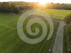 Aerial drone view on a small soccer pitch. Football training ground from above view. Sunset time. Sun flare. Empty green grass