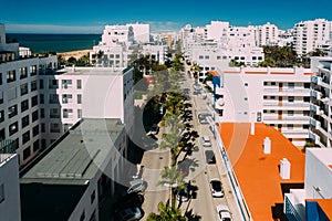 Aerial drone view of street lined with palm trees in tourist Portuguese city of Quarteira, Algarve, Portugal