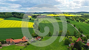 Aerial drone view summer landscape cloudy sky, rapeseed fields, forests, villages, windmills in German countryside.