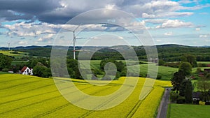 Aerial drone view summer landscape cloudy sky, rapeseed fields, forests, villages, windmills in German countryside.