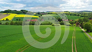 Aerial drone view summer landscape cloudy sky, rapeseed fields, forests, villages, windmills in German countryside.