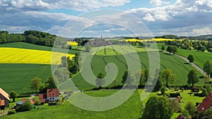 Aerial drone view summer landscape cloudy sky, rapeseed fields, forests, villages, windmills in German countryside.