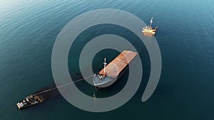 Aerial drone view of sunken cargo ship or tug boat near seaside. Shipwreck vessel with nose of ship above sea water