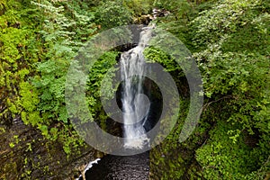 Aerial drone view of a tall waterfall in a narrow canyon surrounded by trees Sgwd Einion Gam, Wales, UK