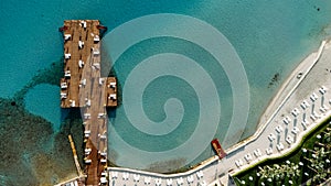 Aerial drone view to the beach with white sand, pier with sunchairs and sea. Luxury summer vacation and resort