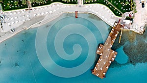 Aerial drone view to the beach with white sand, pier with sunchairs and sea. Luxury summer vacation and resort