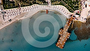 Aerial drone view to the beach with white sand, pier with sunchairs and sea. Luxury summer vacation and resort