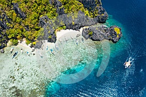 Aerial drone view tourism boats moored at tropical Shimizu Island. Limestone coastal rocks, white sand beach in blue