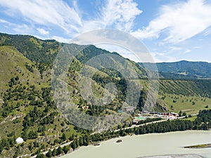 Aerial drone view on a tourist recreation center in the Altai mountains with hotel buildings and pools near green river on a warm