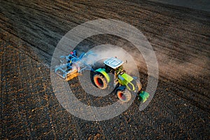Aerial drone view of tractor plowing on the field during evening sunlight