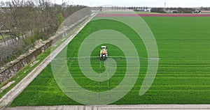 Aerial drone view on a tractor spraying the land. Agricultural famer working the land.