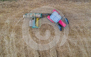 Aerial drone view of tractor working in a wheat field creating straw bales, haystacks