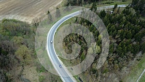 Aerial drone view of the traffic countryside roadway near the green forest. Cars drive through the fork.