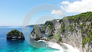 Aerial drone view of tropical beach, sea rocks, turquoise ocean and palm trees. Atuh beach, Nusa Penida island, Bali