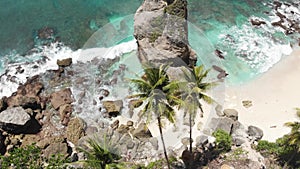 Aerial drone view of tropical beach, sea rocks, turquoise ocean and woman swinging between palm trees. Atuh beach, Nusa