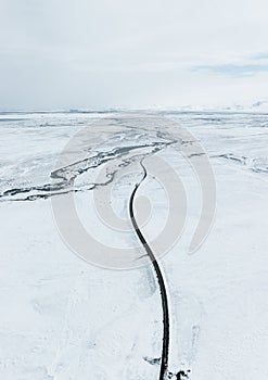 aerial drone view Uphill road landscape in winter at Iceland. Asphalt road with sideways full of snow during winter with