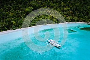 Aerial drone view of a vast scenic tropical sandy beach with lush rainforest and banca boats. Getaway dreamy place raw