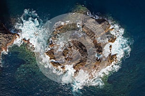 aerial drone view of waves crashing against the rocks of a cliff