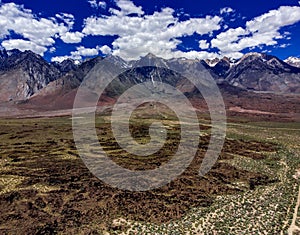 Aerial, drone view of white clouds over snow capped Eastern Sierra Nevada Mountains