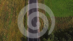 Aerial drone view of wide open empty road deep amongst wilderness forest with rolling hills and mountains