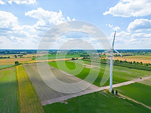 Aerial drone view of wind power turbines, part of a wind farm. Wind turbines on green field in countryside. Wind power plant