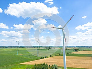 Aerial drone view of wind power turbines, part of a wind farm. Wind turbines on green field in countryside. Wind power plant