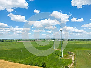 Aerial drone view of wind power turbines, part of a wind farm. Wind turbines on green field in countryside. Wind power plant