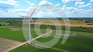 Aerial drone view of wind power turbines, part of a wind farm. Wind turbines on green field in countryside. Wind power plant