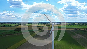 Aerial drone view of wind power turbines, part of a wind farm. Wind turbines on green field in countryside. Wind power plant