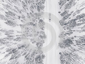 Aerial drone view of winter forest and road covered with snow.