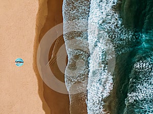 Aerial Drone View Of Woman In Swimsuit Bikini Relaxing And Sunbathing On Round Turquoise Beach Towel Near The Ocean