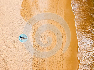 Aerial Drone View Of Woman In Swimsuit Bikini Relaxing And Sunbathing On Round Turquoise Beach Towel Near The Ocean