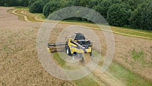 Aerial drone view: yellow combine harvester working in wheat field.