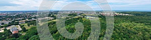 Aerial drone wide panoramic view on green lungs forest surrounding european city during summer, aquapark complex